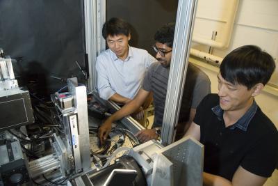 Ling-Jian Meng, right, with his students working at the bench-top XFCT imaging system device.