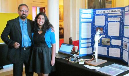 Ananya Cleetus and her father stand beside her display at the White House.
