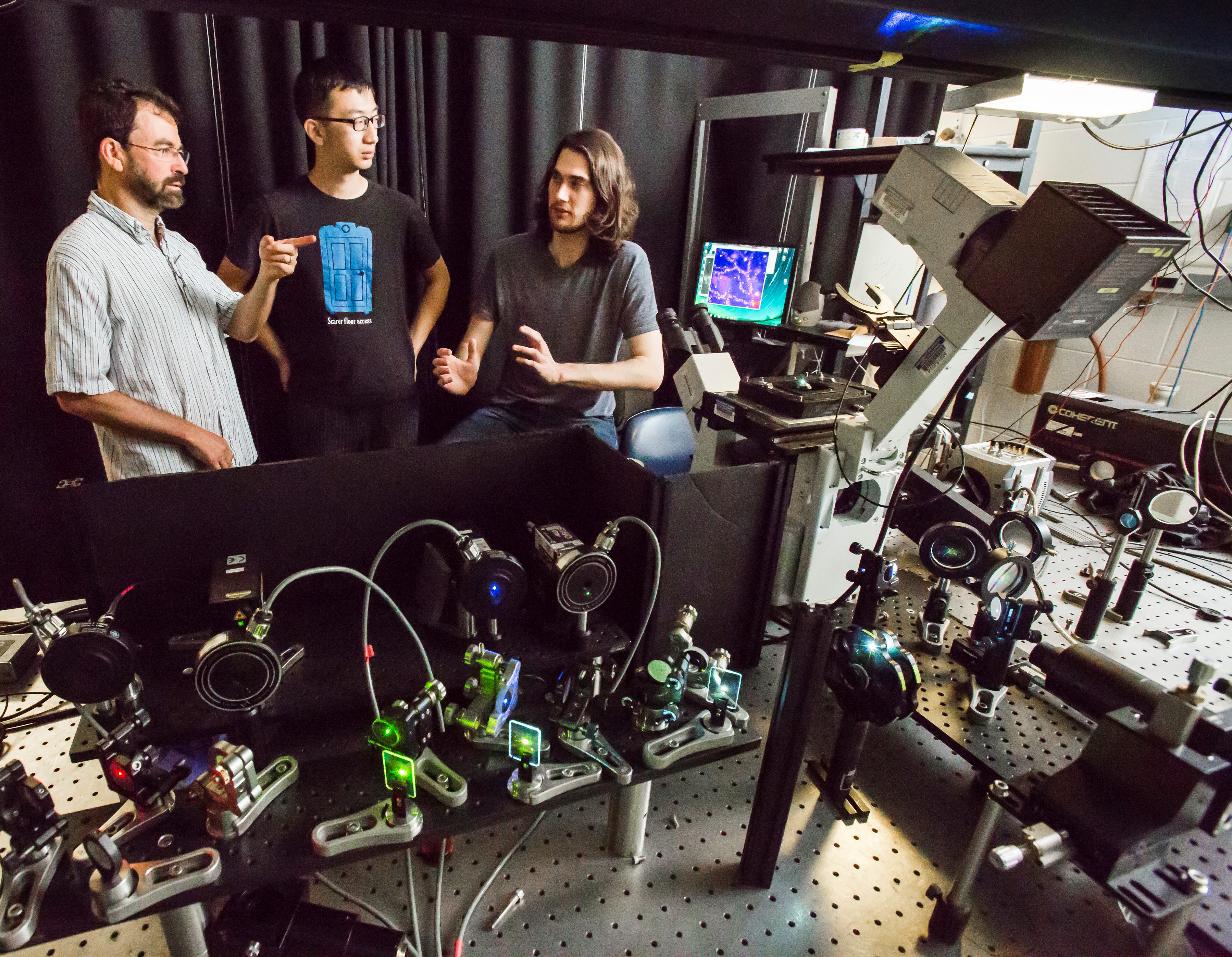 Professor of Physics Paul Selvin (L) discussing next steps in COVID-19 detection with students Chaoyi Jin (center) and Duncan Nall (right). Photo taken prior to the pandemic.