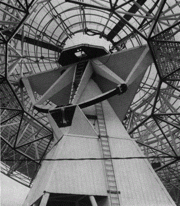 Looking up at the mounting from its northwest side. The dark arc is the track of the chain drive in hour angle, its length permitting motion for 2 1/2 hours before and after meridian passage of a celestial body. The dish is here turned toward the celestial equator.