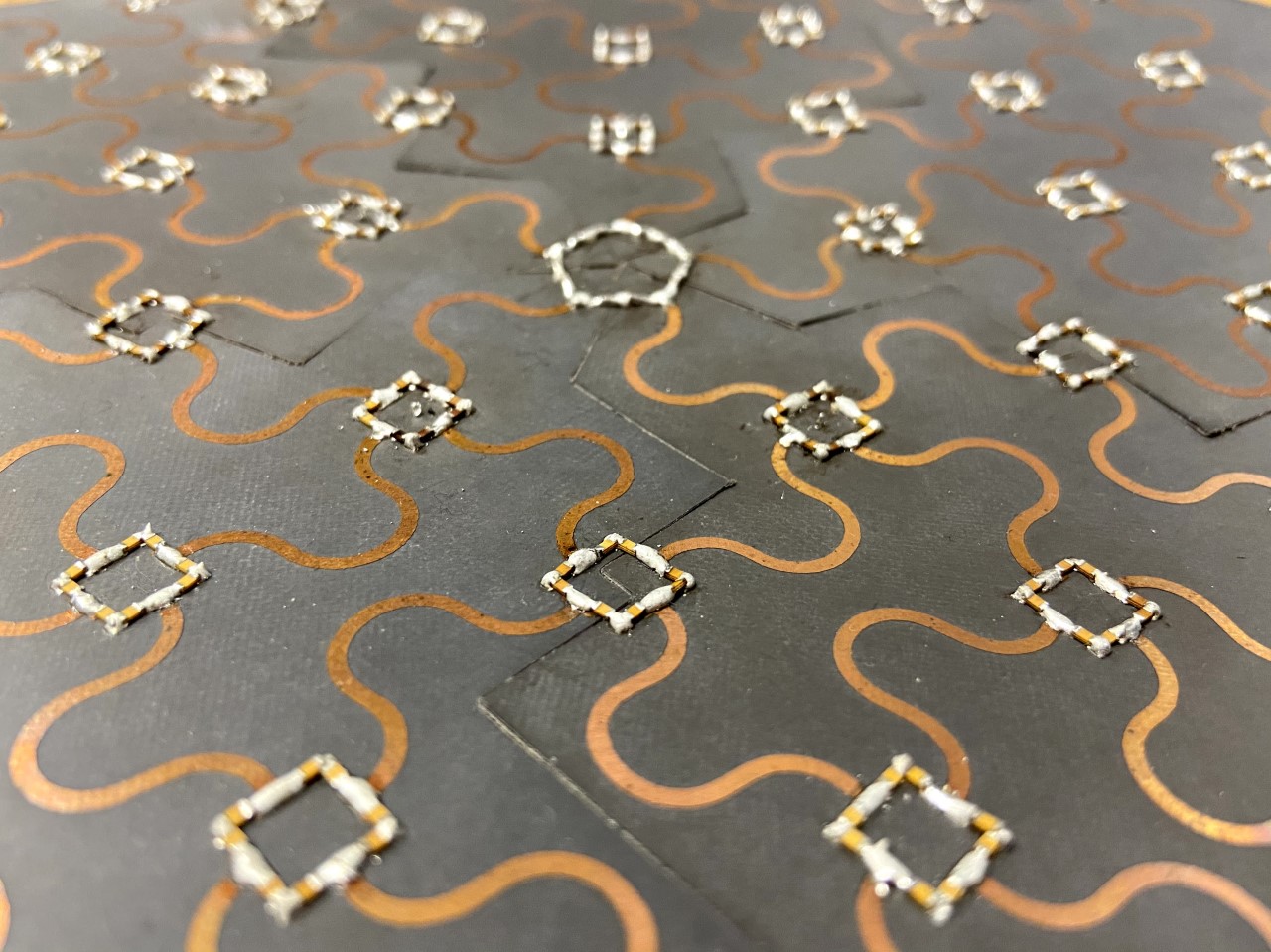 Photo of a metamaterial composed of a pattern of resonators. The defect appears as a pentagon in an otherwise regular array of circuit elements. (Credit: K. Peterson)