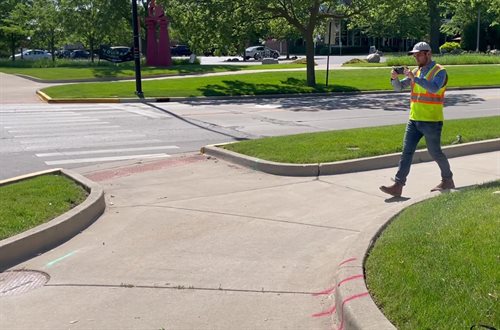 Brandon Yates uses the DeepWalk app to scan a sidewalk curb ramp.